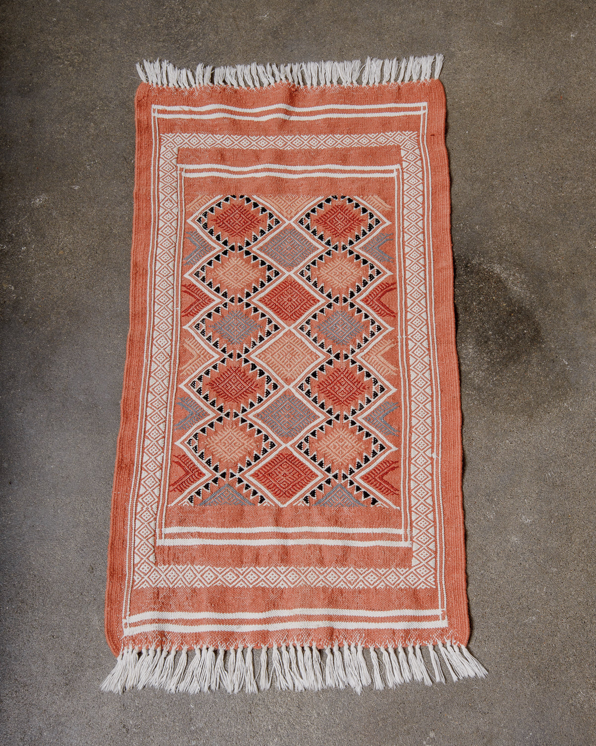 Small Berberlin Vintage Kelim Rug in shades of terracotta and white laying flat on concrete floor.
